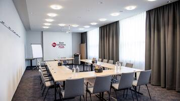A conference room with a long table, chairs, a whiteboard, and a projector.