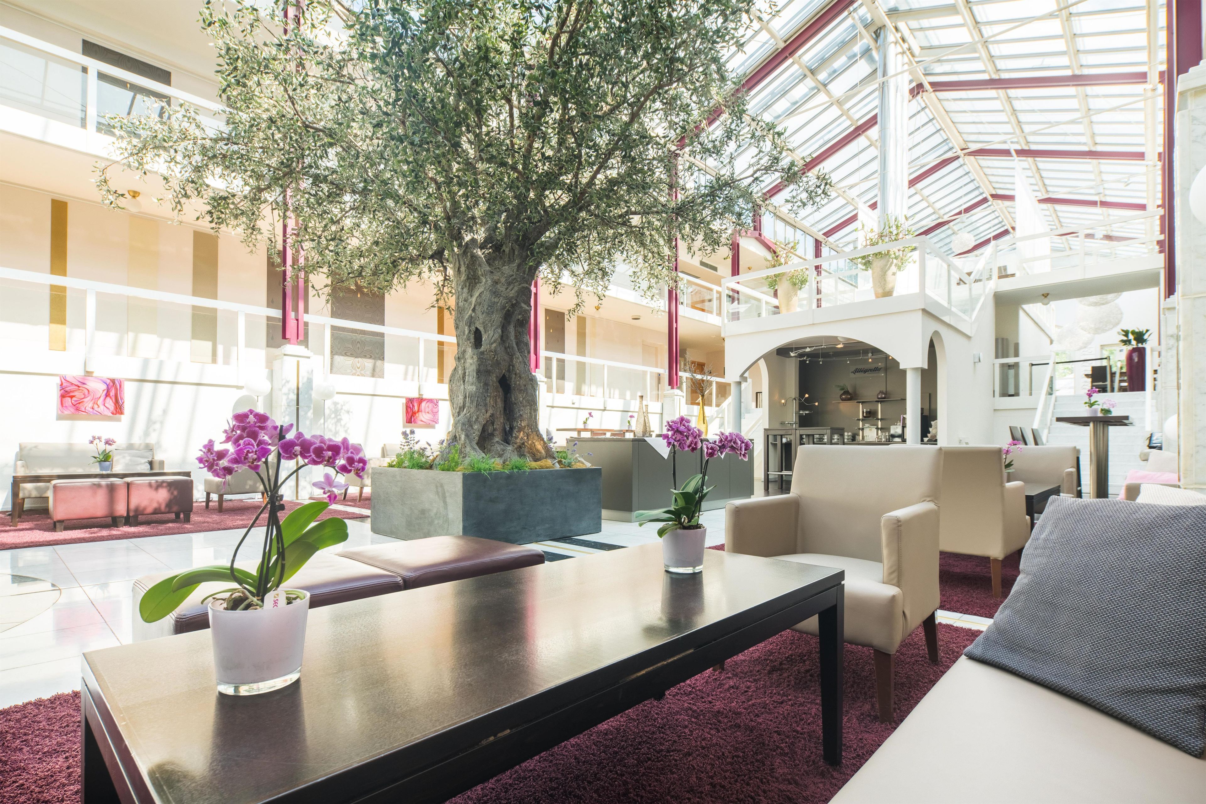 Eine geräumige Lobby mit einem großen Baum, bequemen Sitzgelegenheiten und ansprechendem, modernem Design.