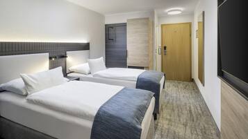 Ein Hotelzimmer mit zwei Betten, einer Holztür, einem Flachbildfernseher und einem Teppichboden.