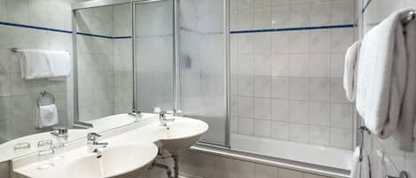 Un baño moderno con dos lavamanos, un espejo grande y una ducha con cerramiento de vidrio.