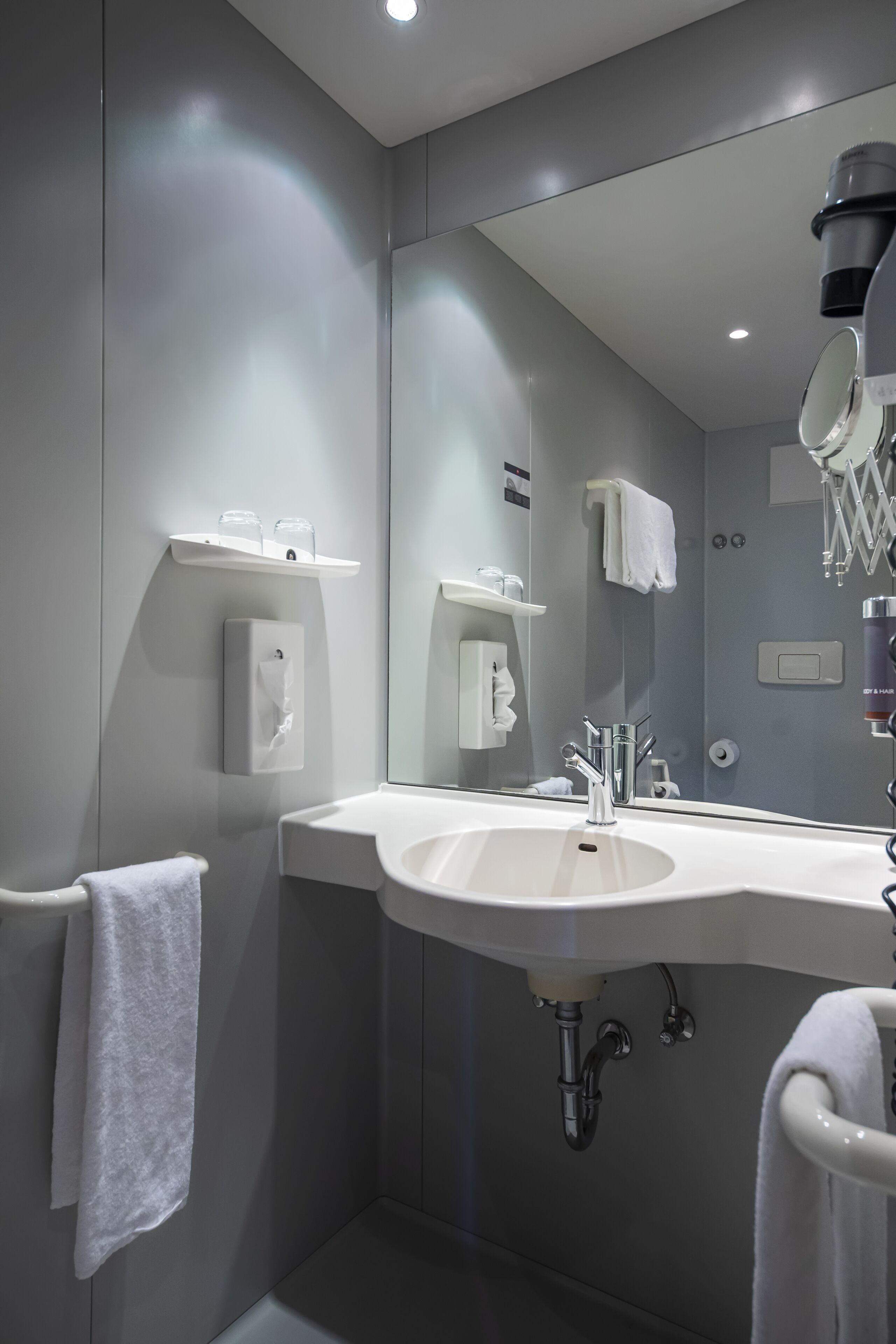A modern bathroom with a large mirror, a sink, and a towel rack.