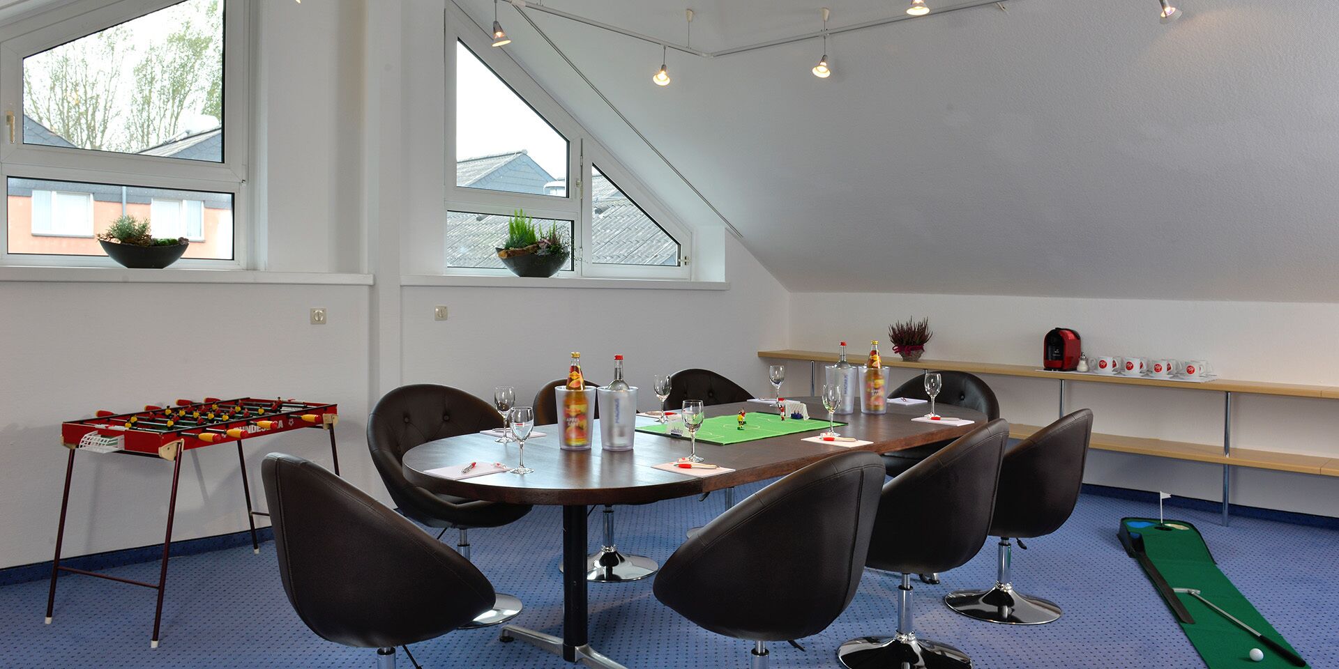 A room with a round table, chairs, a foosball table, a ping pong table, and a billiards table.