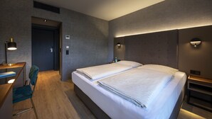 A modern hotel room with two beds, a desk, and a chair. - Hotel am Park Lüneburger Heide (Hodenhagen)