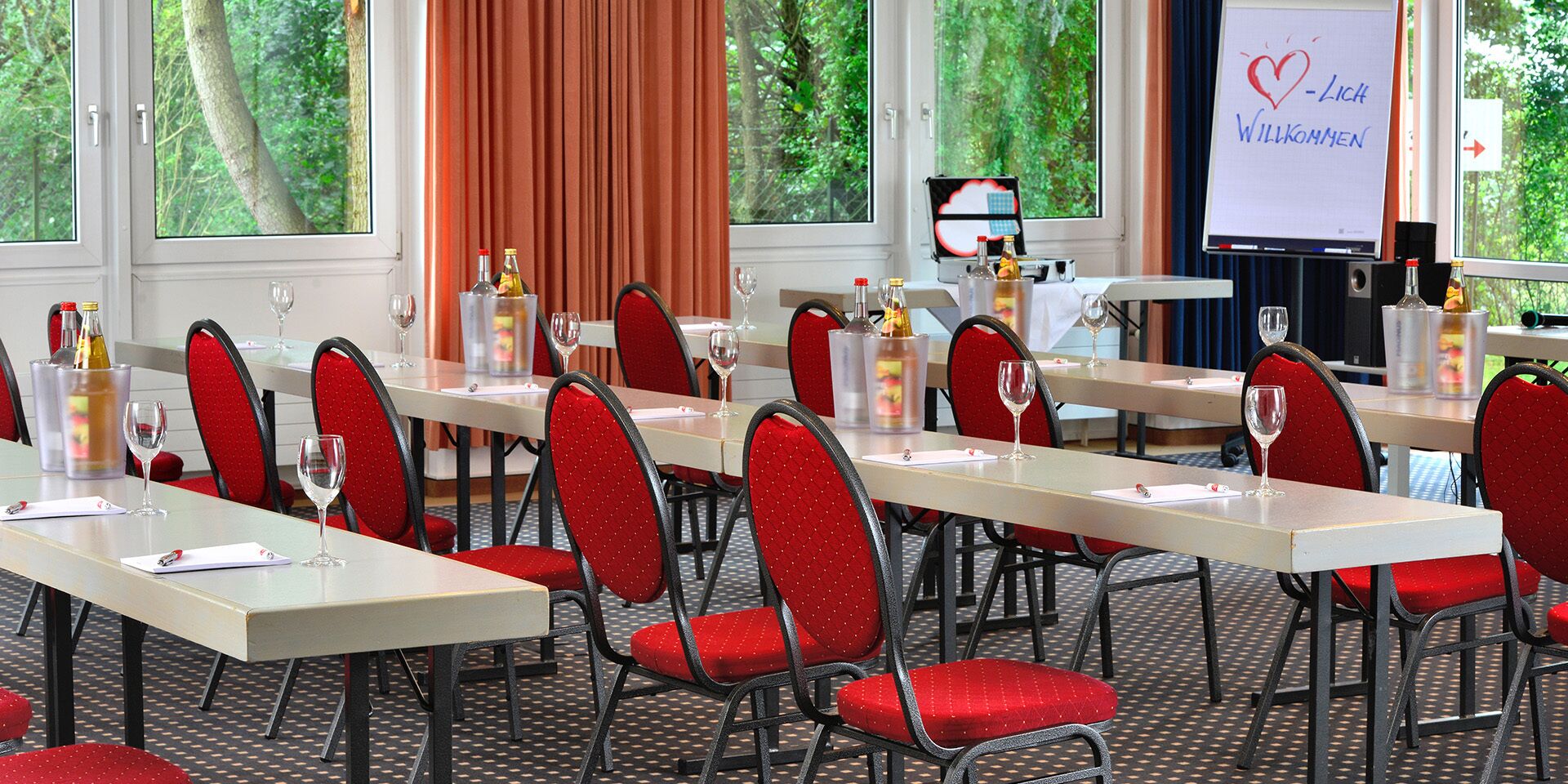 A conference room with red chairs, white tables, and a whiteboard with a heart symbol and text.