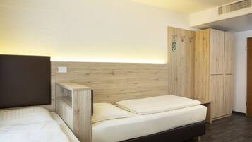 A bedroom with a bed, a wooden headboard, a wardrobe, and a bedside table.