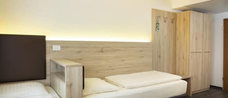 A bedroom with a bed, a wooden headboard, a wardrobe, and a bedside table.