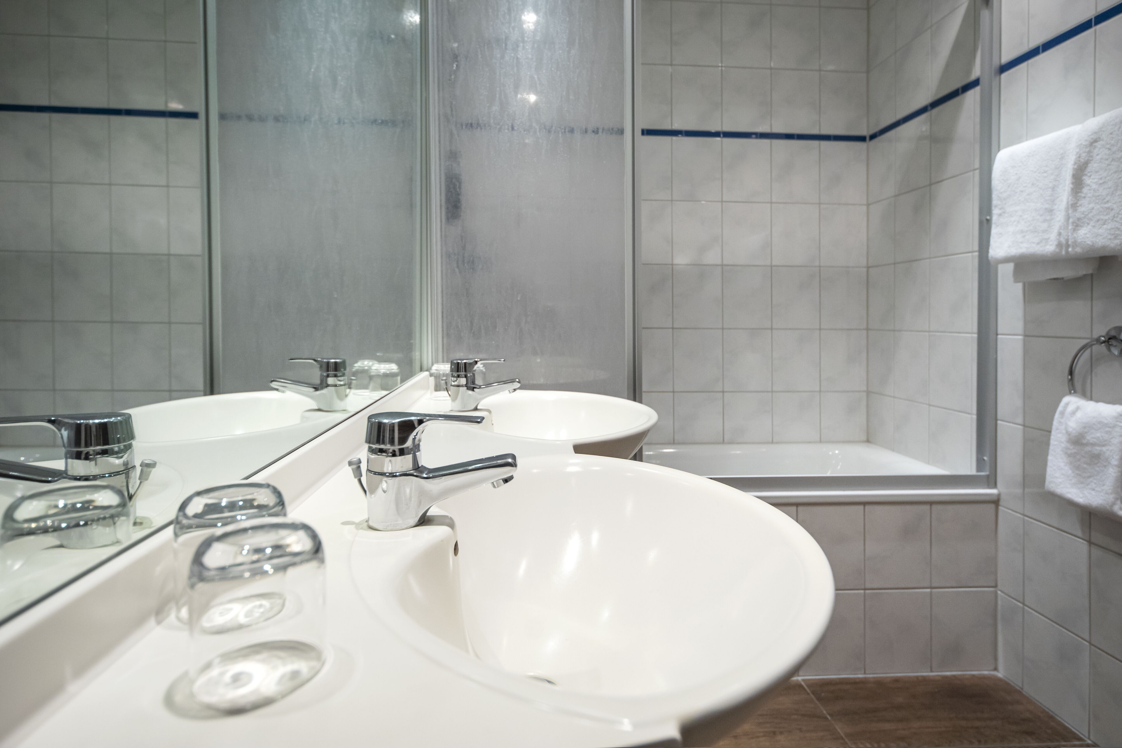 Een badkamer met twee wastafels, een bad en een grote spiegel.