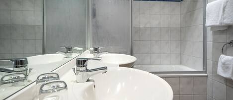 Een badkamer met twee wastafels, een bad en een grote spiegel.