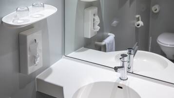 A modern bathroom with a white sink, a mirror, and a towel rack.