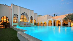 A swimming pool with a tiled edge, surrounded by a building with arched windows and a flat roof. - Gronauer Tannenhof (Bergisch Gladbach)
