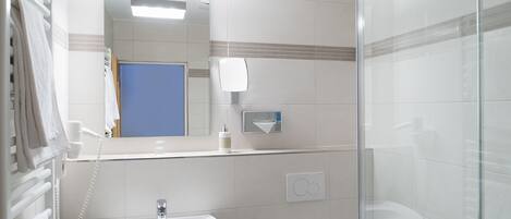 Un baño moderno con cabina de ducha de vidrio, un lavabo blanco y un espejo sobre él.