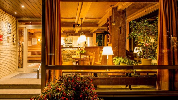 A warmly lit interior with a reception desk, wooden staircase, and potted plants. - Gronauer Tannenhof (Bergisch Gladbach)