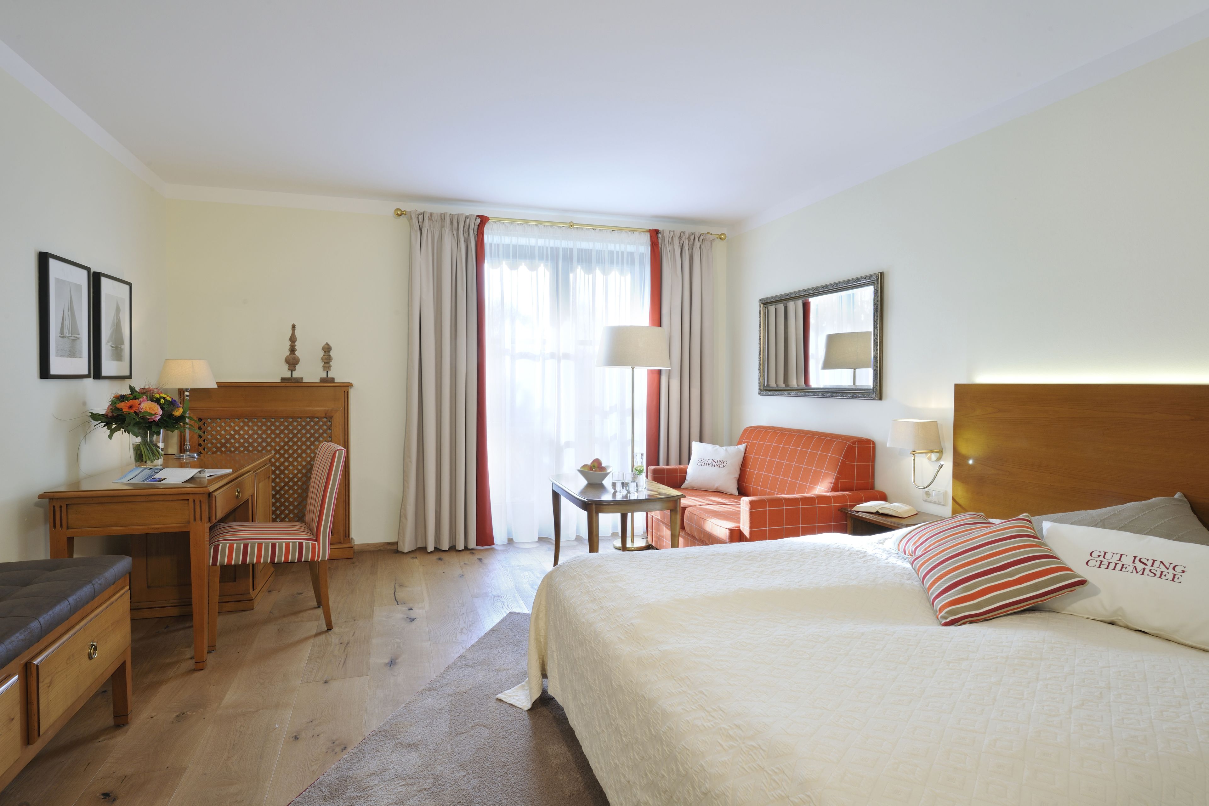 Hotelkamer met een bed, bureau, stoel, nachtkastje en raam met gordijnen.