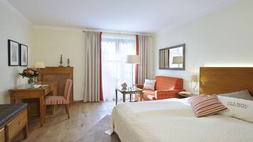 A hotel room with a bed, a desk, a chair, a nightstand, and a window with curtains.