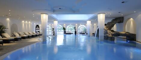 Alberca techada, alberca al aire libre y sombrillas en la alberca