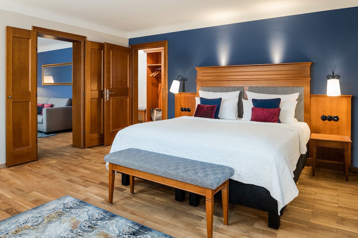 Un dormitorio con una cama grande, cabecera de madera, lámparas de noche y un banco.