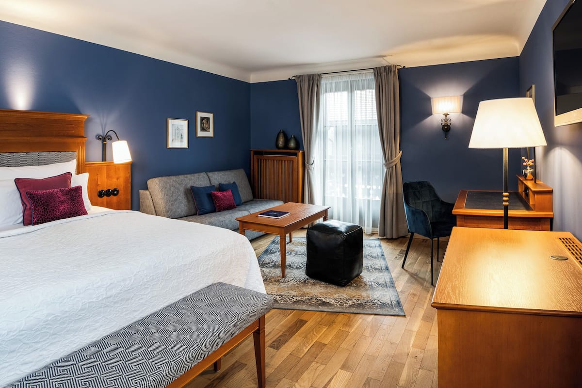 Una habitación de hotel con una cama grande, un sofá, un escritorio y una silla.