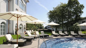 Una piscina techada, una piscina al aire libre, sombrillas