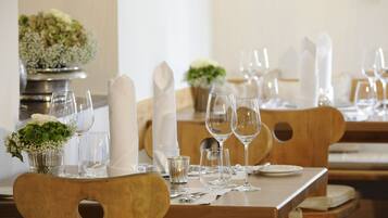 Une table à manger dressée avec des serviettes blanches, des verres transparents et un petit vase rempli de fleurs.