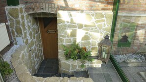 A stone-built sauna with a wooden door labeled "Sauna," a potted plant, and a lantern on the ground. - Hotel Elefant (Schwerin)