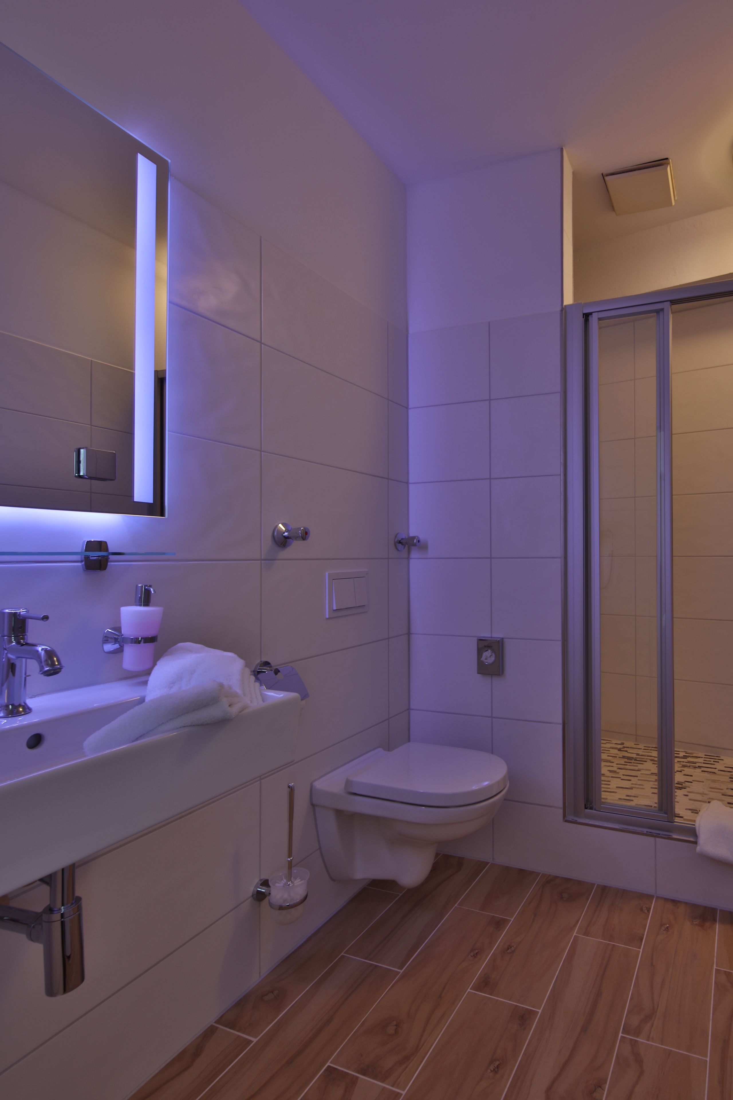Un baño moderno con lavamanos, espejo y retrete blancos.