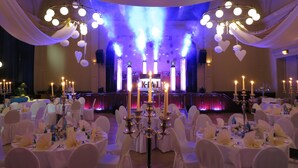 A banquet hall with round tables set for a formal event, featuring white tablecloths, chairs, and candle centerpieces. - Hotel Elefant (Schwerin)
