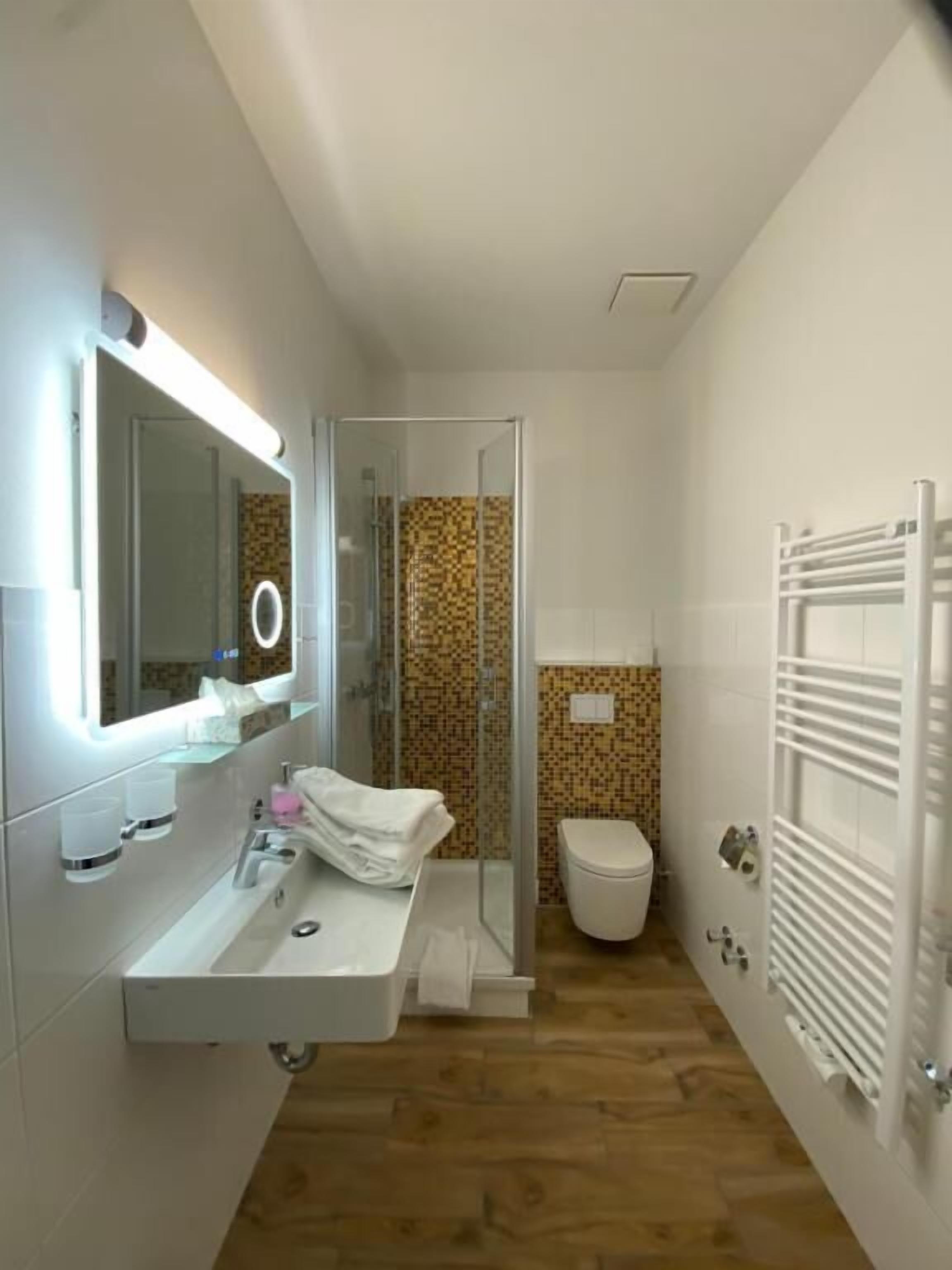 A bathroom with a sink, mirror, shower, and toilet.