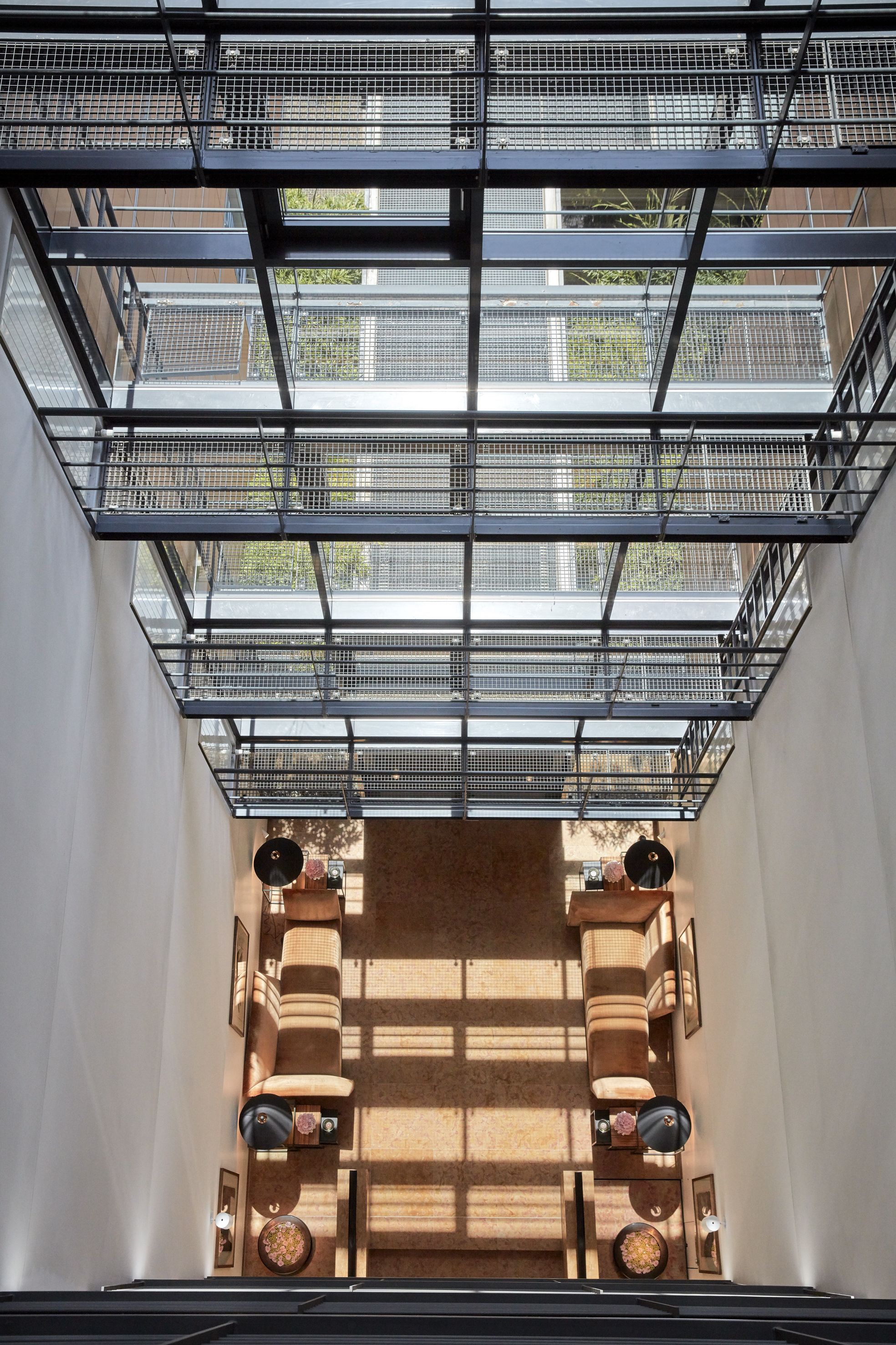 Ein modernes Interieur mit hoher Decke und einem gitterartigen Metallbau. Zwei Sofas und ein kleiner Tisch mit Dekorationselementen sind zu sehen.