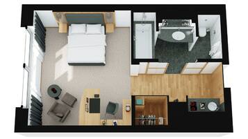 Distribución de una habitación de hotel con cama, escritorio, silla, una mesita, sofá, baño con lavamanos e inodoro, y zona de ducha.