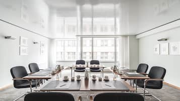 A conference room with a long table, black chairs, and framed pictures on the walls.