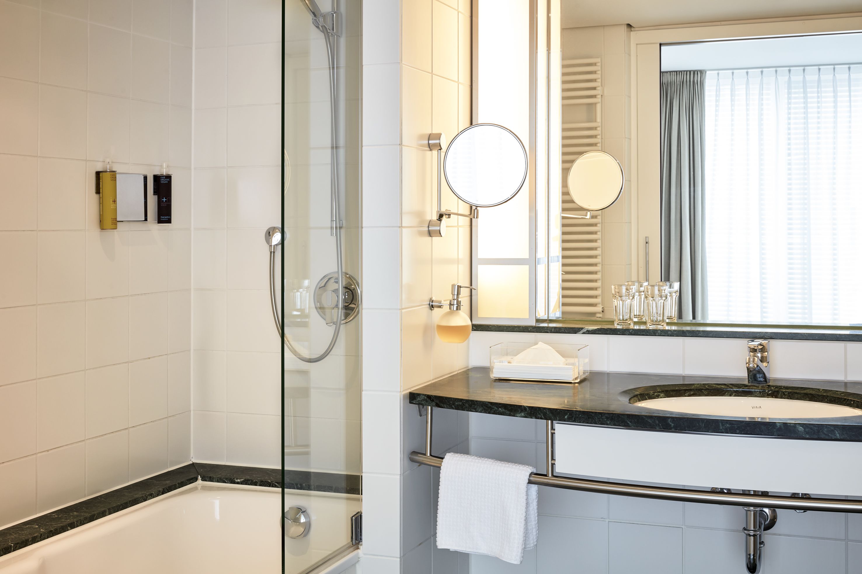 Un baño moderno con ducha de vidrio, tocador con lavamanos y un espejo grande.