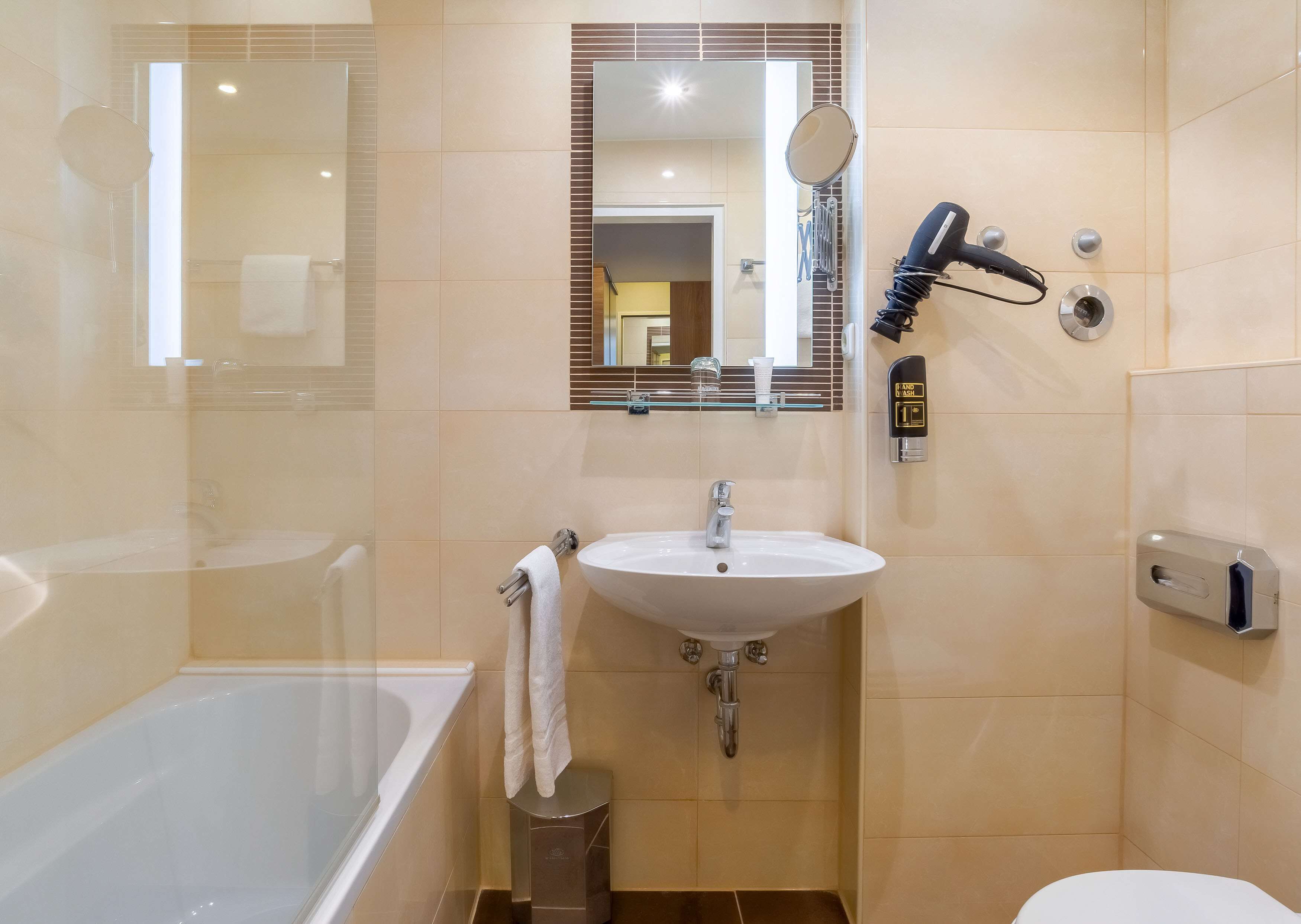 Une salle de bain équipée d’une baignoire, d’un lavabo, d’un miroir et d’un sèche-cheveux.