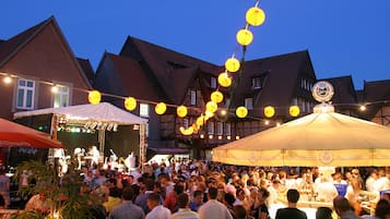 Un evento al aire libre concurrido, con carpas y un escenario, rodeado de edificios tradicionales.