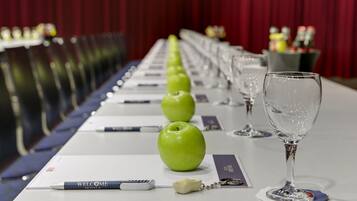 Una mesa de conferencias con una hilera de manzanas verdes, un bolígrafo, un llavero y una copa de vino.
