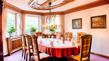 A dining room with a round table, wooden chairs, and a chandelier.