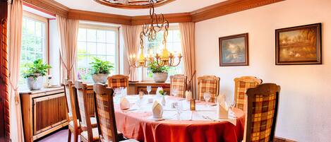 A dining room with a round table, wooden chairs, and a chandelier.