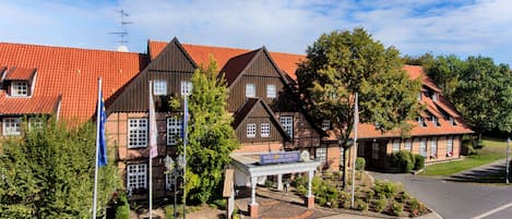A traditional building with a red-tiled roof, multiple windows, and a sign indicating it is a hotel.