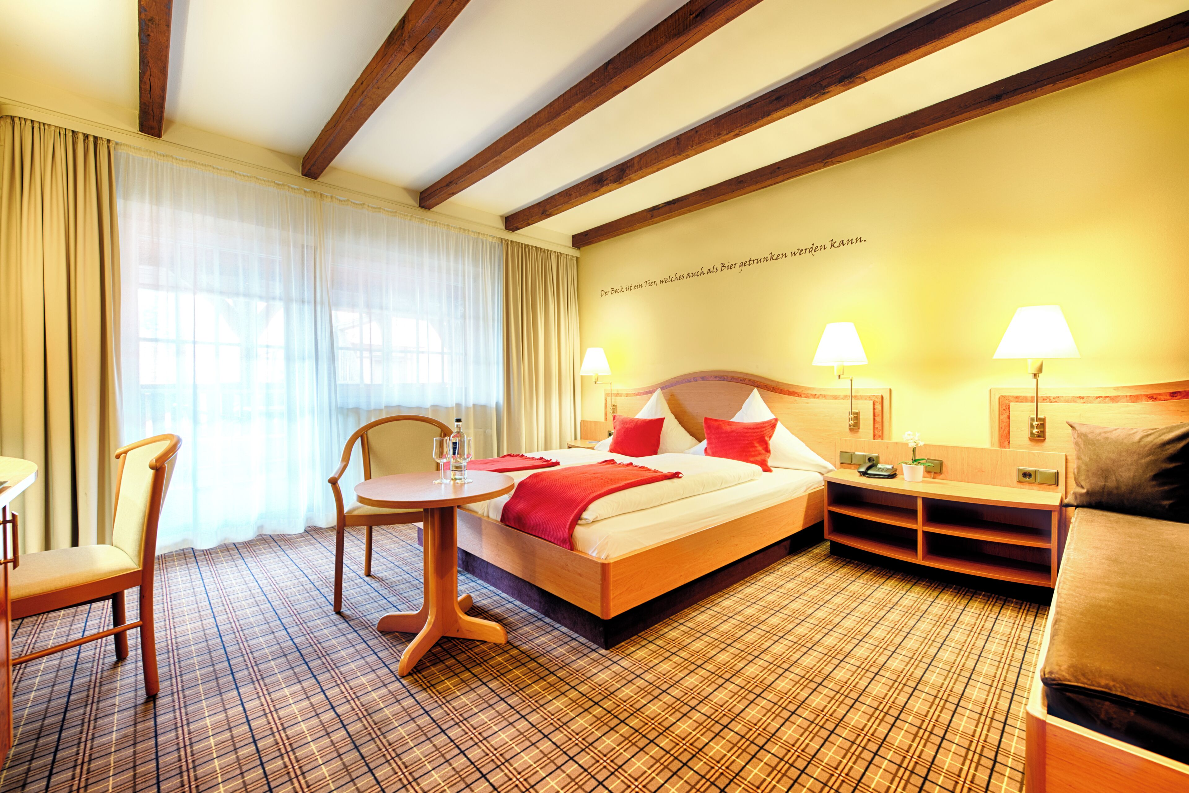 Una habitación de hotel con cama, escritorio, silla y lámpara.