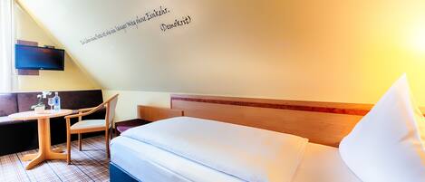 A hotel room with a bed, a desk, and a chair.