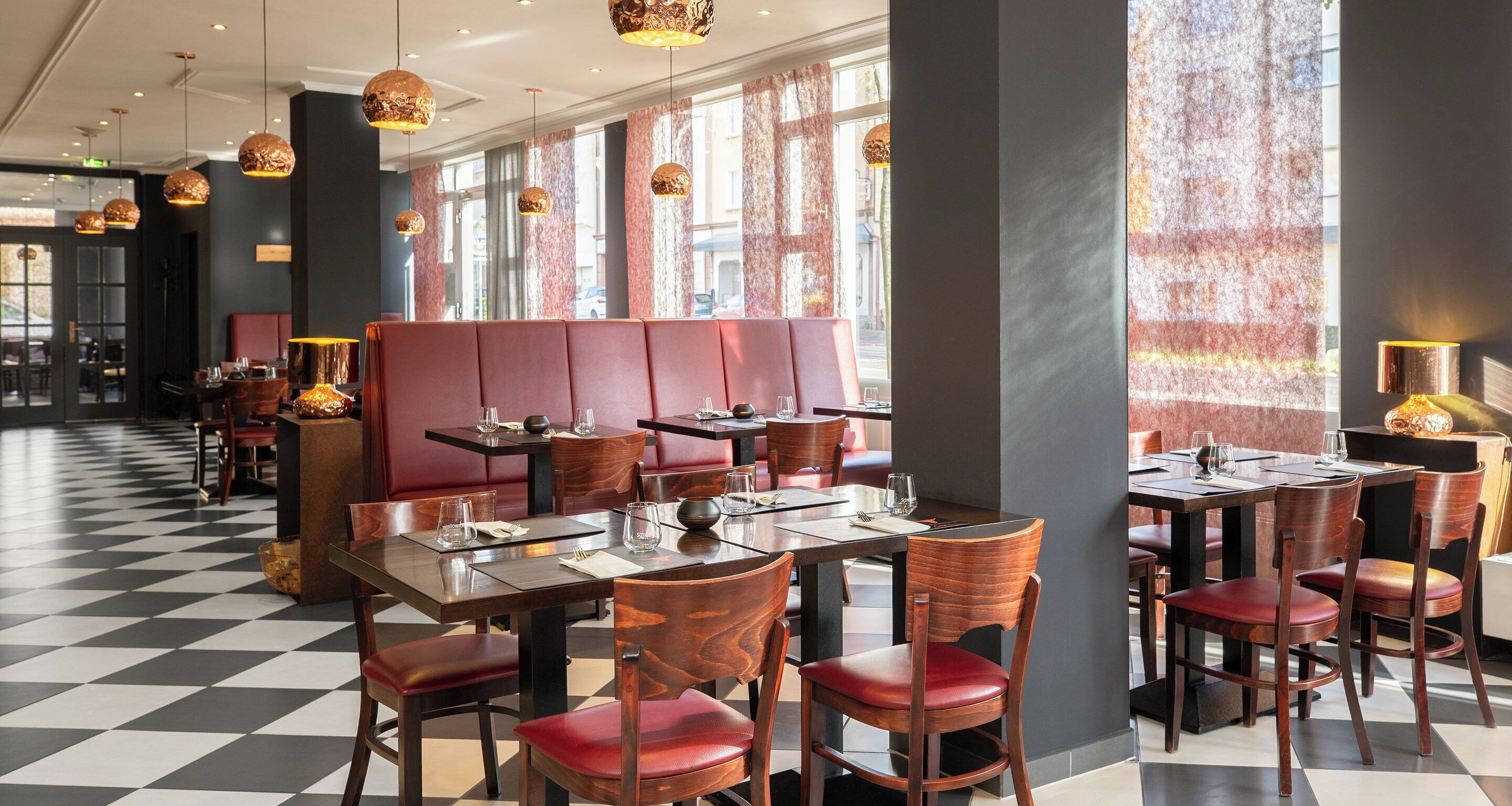 Ein Restaurant mit Schachbrettfußboden, Holztischen und roten Sitzbänken.