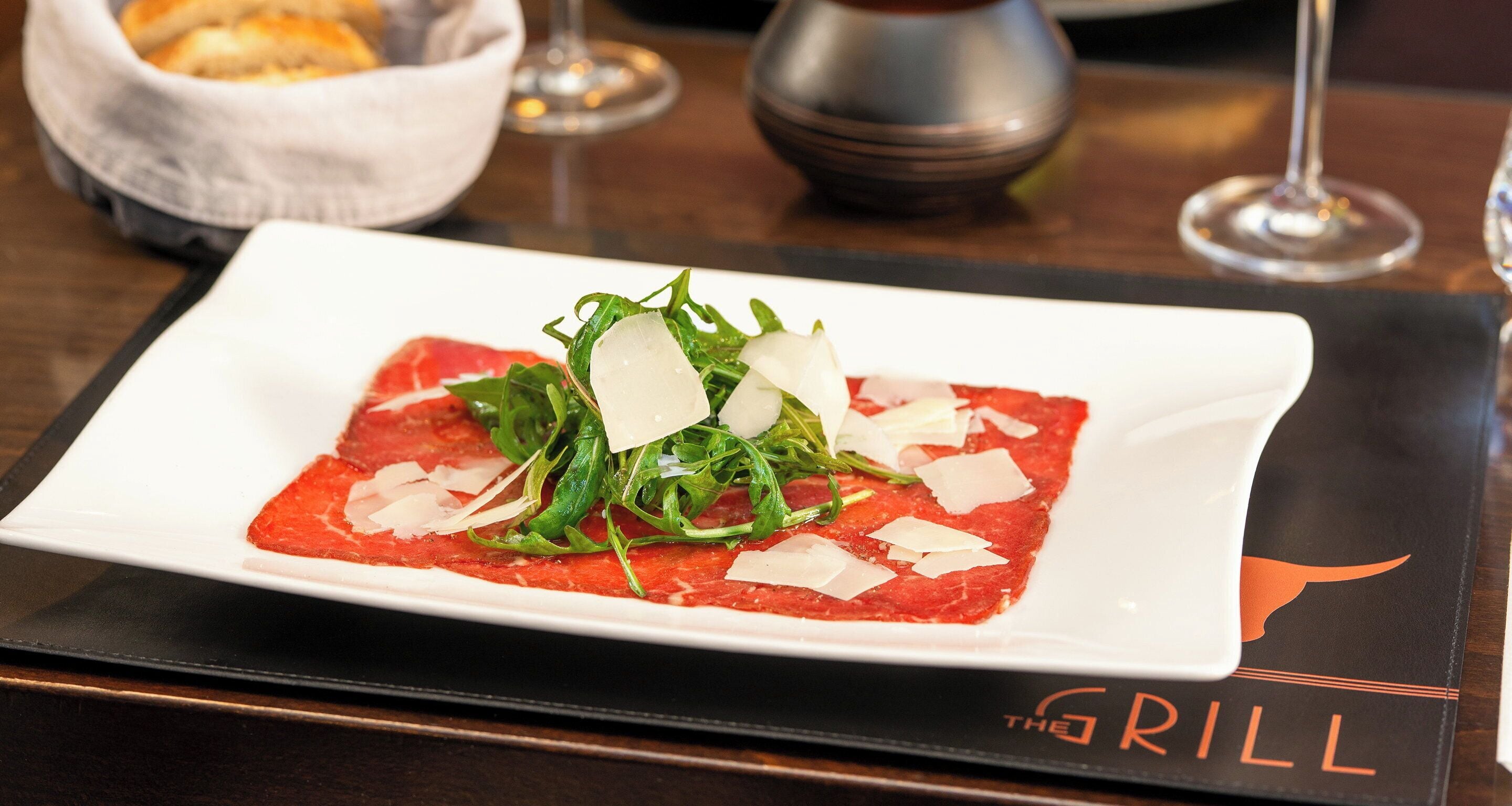 Un plato de comida sobre una mesa con un mantel individual que dice 'The Grill'.