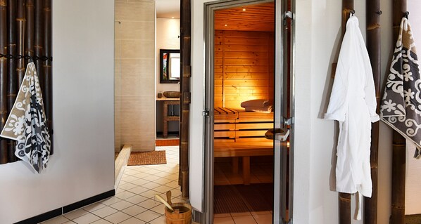 A sauna room with a bench and a bench seat, a wooden door, and a towel rack with towels.