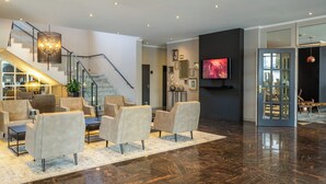 A spacious living area with a modern staircase, comfortable seating, a flat-screen TV, and a large window.
