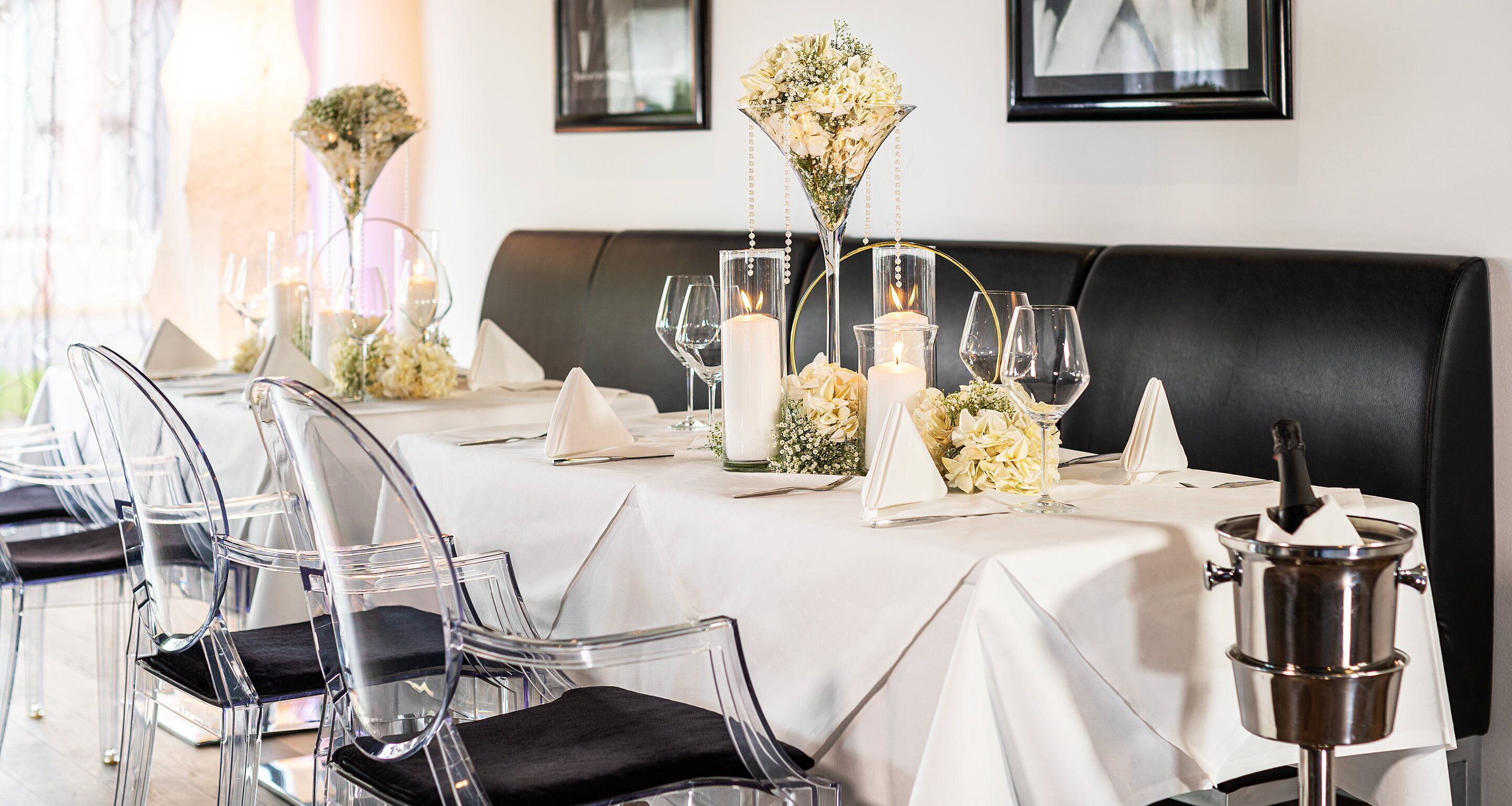 Une table à manger agrémentée de chaises transparentes, d’une nappe blanche, de bougies et de compositions florales.
