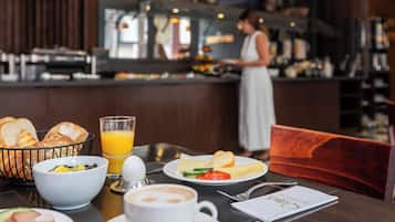 A breakfast setting with bread, fruit, cheese, and a glass of orange juice on a table.