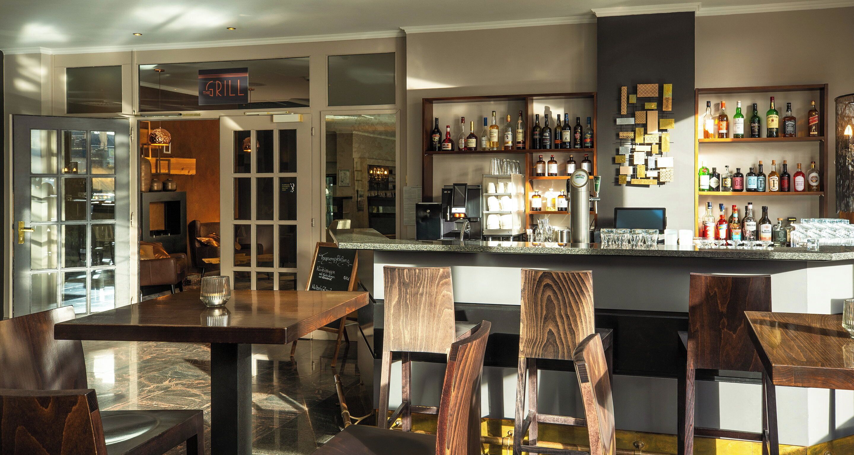 A bar area with wooden furniture, a variety of liquor bottles, and a chalkboard menu.
