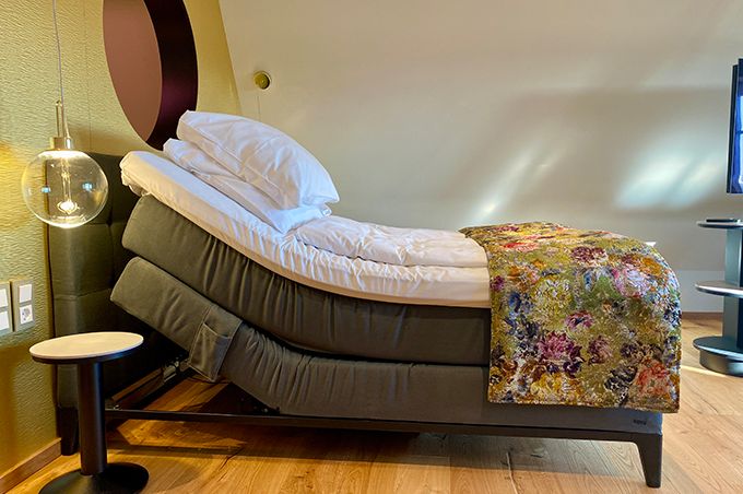 A bed with a headboard, a bedside table, and a floor lamp.