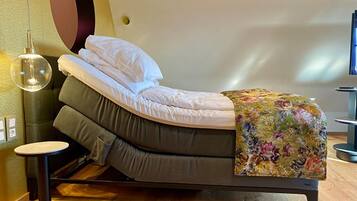 A bed with a headboard, a bedside table, and a floor lamp.