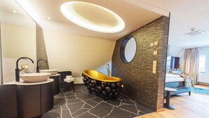 Un baño moderno con una bañera independiente, un espejo grande y un tocador doble.