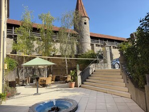 Un patio con mobiliario exterior, una fuente y una torre de piedra.